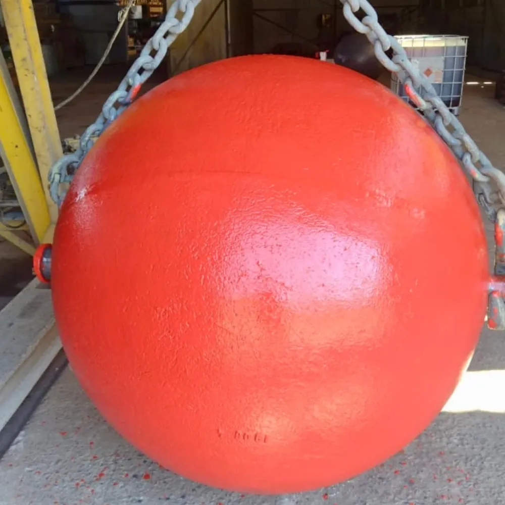 Esfera metálica DropBall vermelha içada por correntes na oficina, pronta para operação